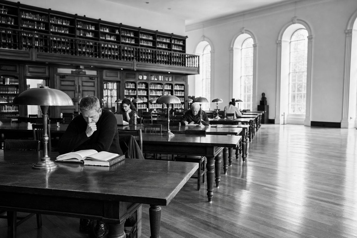 An open library reading room with UK adult learners studying at long polished tables